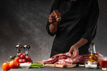 Cooking fresh pork ribs. For roasting and cooking. Chef sprinkles with seasoning for roasting. Classic American dish. Sale of meat, butcher shop. With space for inscription or advertising.