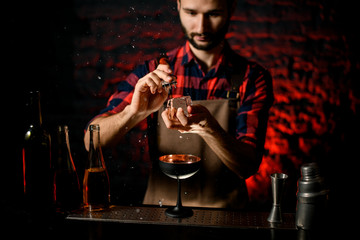professional bartender man holds large piece of iceand breaks it