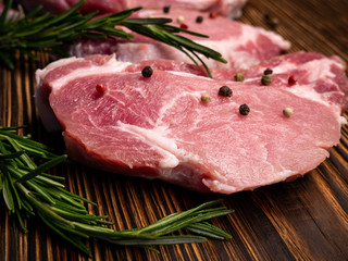 Raw meat, steak on a wooden Board. Spices, garlic, rosemary, peppers. Ready for cooking and roasting.
