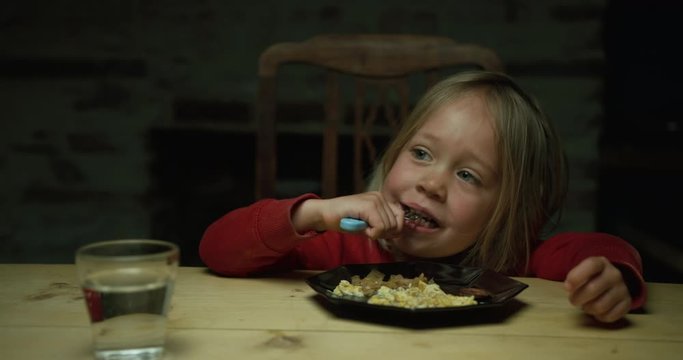 Little boy eating breakfast of scrambled eggs at table