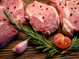 Raw meat, steak on a wooden Board. Spices, garlic, rosemary, peppers, tomato. Ready for cooking and roasting.
