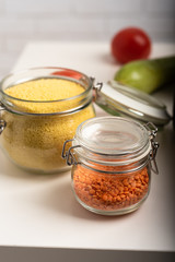 Close-up view of two jars with lentil and wheat on a kitchen table. Preparation for cooking
