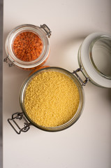 Top view of two jars with cereals. Lentil and wheat in jars. Kitchen table, preparation for cooking