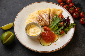 pancakes with red caviar on black background
