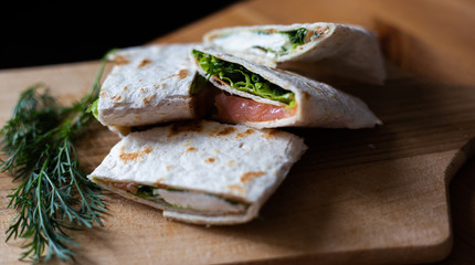 
Healthy food pita bread cutaway appetizer tartilla with soft cheese dill and lettuce on a wooden tray and on a gray kitchen towel