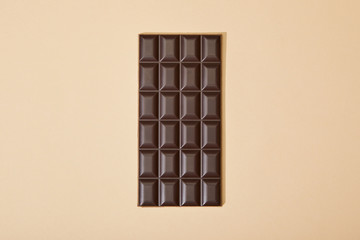 top view of sweet dark chocolate bar on beige background