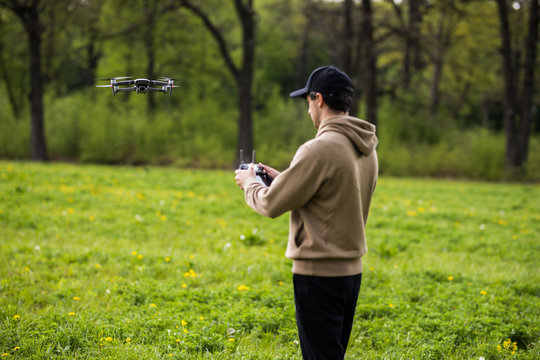 Young man with flying drone on Sunny green nature background