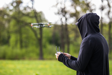 Young man with mask use remote control for drone at natural green background. Young man with drone ready for spy people. Spy drone.