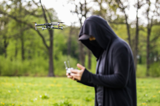 Young unrecognizable man manage drone while spying standing on green nature background.