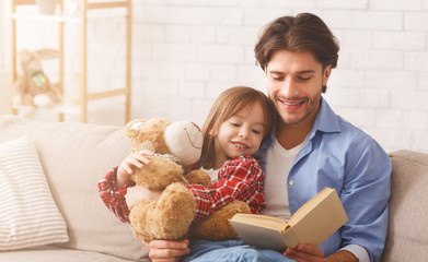 Young dad reading fairy tales to his little daughter