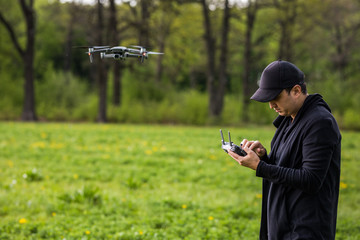 Young man and drone, quadrocopter in a forest on a green background.