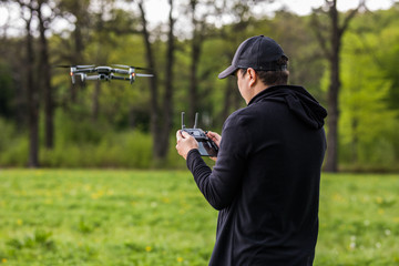 Young man and drone, quadrocopter in a forest on a green background.
