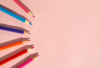 Background of colorful pencils on pink background. Back to school, education and learning concept. Minimalist isometric concept.