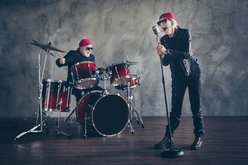 Full body photo of retired lady man rock popular band perform concert play drum instruments sing song cool mic wear trendy rocker leather outfit bandana isolated grey concrete wall background