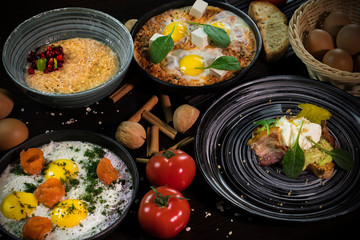 Beautiful dishes decorated with tomatoes, walnuts and cinnamon on a dark background : Eggs with salmon, shakshuka, porridge with cranberries, eggs Benedict with bacon