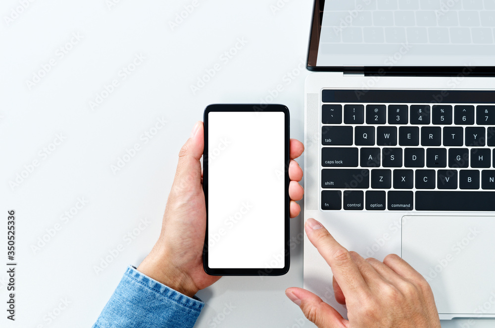 Poster using smart phone from above. white blank screen. laptop on white background.
