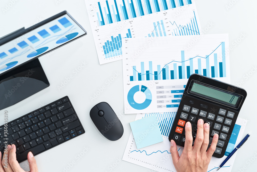 Aufkleber Business man using calculator from above. Finance and accounting concept. Many graphs on reports and desktop computer screen.