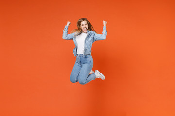 Overjoyed young woman girl in casual denim clothes posing isolated on orange background studio...