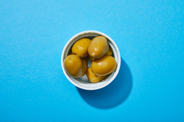 top view of olives in bowl on blue colorful background
