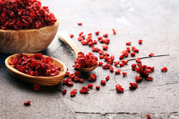 Pile of dry barberries in a wooden bowl on rustic table