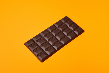 sweet dark chocolate bar on orange colorful background