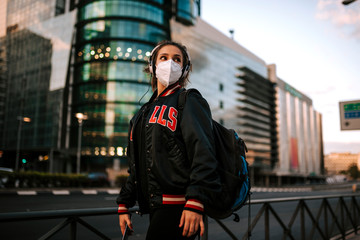 young girl dressed in sport wears medical mask on city street in spain. Coronavirus pandemic Covid-19