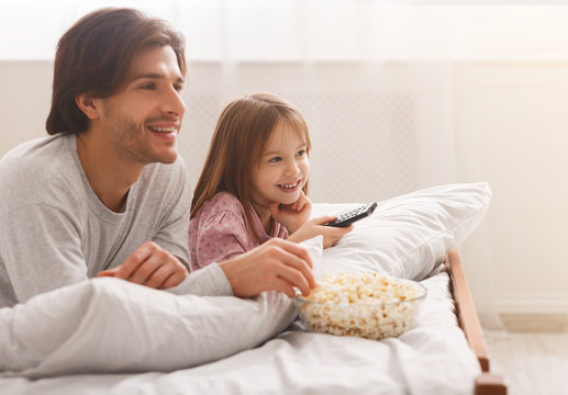 Happy family of two watching movies, eating popcorn
