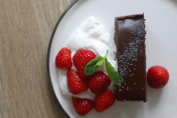 Piece of chocolate and poppy seed cake with whipped cream and strawberries. Top view.
