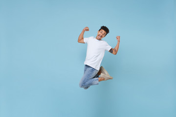 Joyful young african american guy in casual white t-shirt posing isolated on pastel blue wall...