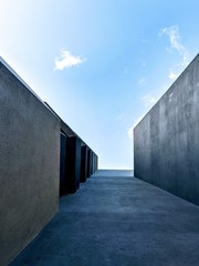 Fototapeta premium Dark grey walls leading into an expansive blue sky