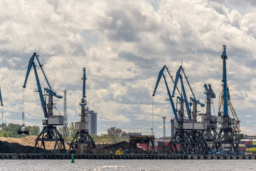 Fototapeta na wymiar view from the river to the freight port with cranes and cargo containers.