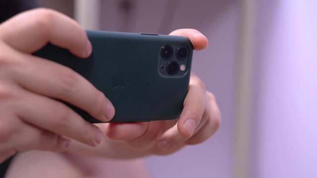 May 01, 2020, Rostov-on-Don, Russia: Human hands holding Apple iPhone 11 Pro of midnight green color with three cameras on the back side, and making photo or video shooting.