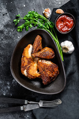 Half a grilled chicken on a plate. Black background. Top view