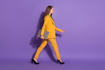 Obraz na płótnie Canvas Full length profile side photo of confident boss lawyer girl hold laptop go walk copyspace conference wear trousers isolated over purple color background
