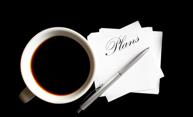 Office table with supply and coffe cup. View from above for text Plans