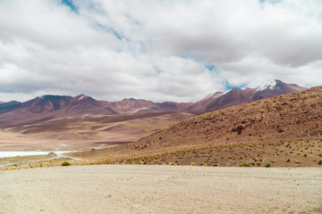 Dry, barren landscape mountain background. Dramatic desert, snowcapped mountains wilderness. Mountain range view. Salt Flats of Uyuni, Bolivia. Copy space, blue sky, nature, hiking, and sand dust