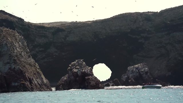 Coastal scenery of Peru with tourist in a boat watching the wildlife on the rock