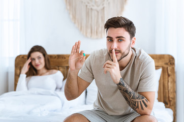 Male secret concept. Man holds blue pill in his hand and presses finger to his lips