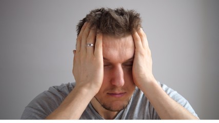 Stressed Young Man Squeezing Head With Hands, Suffering From Headache. 