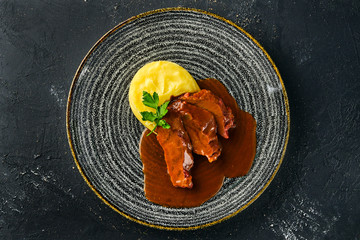 Overhead view of roasted beef slices with wine sauce and mashed potato