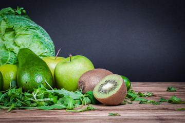 Vegetarian healthy food. Source of protein for vegetarians. Healthy eating: vegetable, avocado, kiwi, leaf vegetable, apple, lime on dark background.