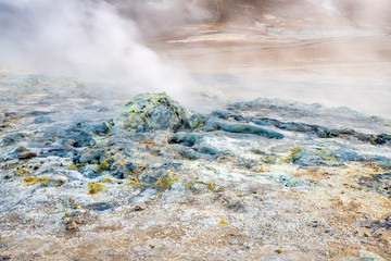 Hverarond geothermal area in Myvatn, Iceland. Steam vents and hot pools, muddy hot soil, sulfur smoke and colorful textures and patterns during blue hour.
