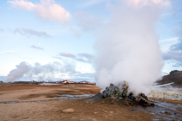 Hverarond geothermal area in Myvatn, Iceland. Steam vents and hot pools, muddy hot soil, sulfur smoke and colorful textures and patterns during blue hour.