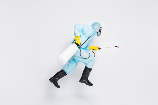 Full body profile side photo man jump run hurry disinfect covid spread house wear white hazmat suit yellow rubber latex gloves goggles use sprayer isolated gray color background