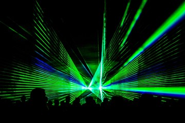 Green laser show nightlife club stage with party people crowd. Luxury entertainment with audience silhouettes in nightclub event, festival or New Year's Eve. Beams and rays shining colorful lights - obrazy, fototapety, plakaty