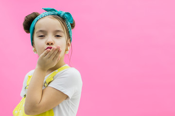 Portrait of beautiful charming brunette girl happily sending air kiss in camera over pink background.