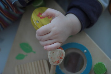 Palm hand of a young baby, holding a wooden toy.