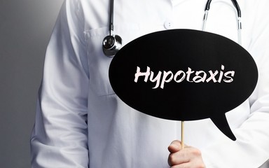 Hypotaxis. Arzt mit Stethoskop hält Sprechblase in Hand. Text steht im Schild. Gesundheitswesen, Medizin