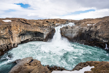 Aldeyjarfoss waterfall canyon in the highlands of Iceland. Basalt columns and powerful water flow on a sunny day.