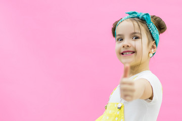 Positive girl keeping thumb up wearing yellow and white clothes.